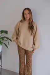 Conjunto de sweater oversize color beige y pantalón acampanado con estampado animal print.