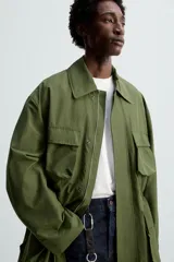 Parka verde militar de corte relaxed fit confeccionada en tejido técnico ligero. Cuello solapa y manga larga. Bolsillos de plastrón con solapa en delantero. Cintura ajustable en interior. Cierre frontal con cremallera oculta por solapa con botones a presión.