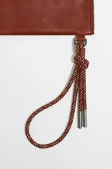 Neceser negro de piel con estructura blanda, asa de mano de cordón extraíble, logo metálico, acabados metálicos plateados, bolsillo interior y cierre con cremallera. Interior con etiqueta de tejido BIMBA Y LOLA.