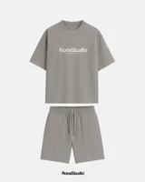 Conjunto deportivo gris compuesto por remera de manga corta con logo estampado y bermuda con cintura elástica ajustable con cordón.