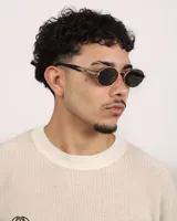 Lentes de sol ovalados con marco dorado y lentes oscuros.