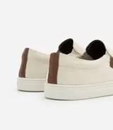 Championes slip on color crudo, con elásticos laterales y detalle de etiqueta marrón con logo en el lateral.