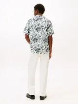 Camisa de manga corta con cuello solapa y estampado floral en tonos negro, blanco y verde.