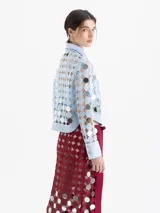 Camisa de manga larga color celeste claro, confeccionada en guipur con apliques circulares espejados. Posee cuello y puños en tela lisa y cierre frontal con broches snap forrados. Incluye un top interno liso al tono.