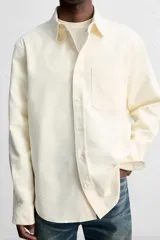 Camisa color crudo de algodón con acabado cepillado, corte relaxed fit, cuello solapa, manga larga con puño abotonado, bolsillo de parche en el pecho, efecto lavado y cierre frontal abotonado.