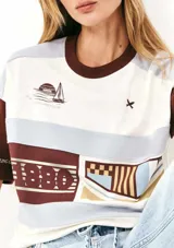 Camiseta de mangas cortas con cuello redondo y corte amplio. Presenta un diseño con bloques de color y estampados con motivos náuticos y geométricos.