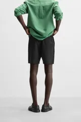 Bermuda negra regular fit confeccionada en tejido de algodón con estructura. Cintura elástica ajustable con cordón, bolsillos laterales y bolsillo trasero de vivo.
