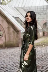 Vestido verde metalizado con escote en V pronunciado, mangas 3/4 y frunce en la cintura.