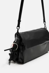 Bandolera negra con solapa y cierre magnético. Incluye llavero decorativo con forma de estrella. Tiene correa de hombro ajustable y extraíble. El interior cuenta con tres compartimentos, uno con bolsillo con cierre.