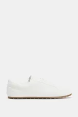 Zapato deportivo tipo blucher color blanco, con cuerpo en relieve y detalle de pespunte en contraste. Cierre mediante cordones y suela de 2 cm de altura.