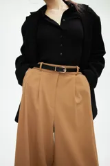 Pantalón ancho color marrón claro con pinzas, bolsillos laterales y trabillas para cinturón.
