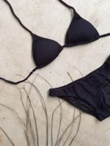 Conjunto de bikini verde esmeralda con textura acanalada. El corpiño es de triángulos movibles con tiras finas para atar al cuello y a la espalda, y tiene almohadillas desmontables. La bombacha es vedetina ancha con laterales fijos.