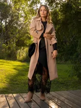 Trench color beige, de corte largo y con cintura ajustable, ideal para combinar en diversas ocasiones.