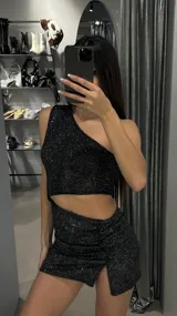 Minivestido negro con brillos plateados, de un solo hombro y corte ajustado con abertura en la pierna.