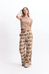 Pantalón wide leg estampado con diseño de conchas marinas color marrón sobre fondo blanco.