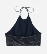 Blusa cropped de lentejuelas negras con cuello halter y espalda descubierta.