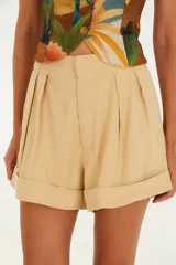 Short de vestir color beige, con cintura alta, pliegues frontales, bolsillos laterales y ruedo con dobladillo.
