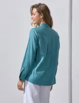 Camisa blanca de lyocell, marca Dash. Tiene cuello con solapa, abertura central con botones, mangas largas regulables con presilla y botón, y dos bolsillos delanteros aplicados.