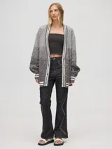 Cardigan tejido de punto con patrón de rombos en degradé de grises y blanco. Tiene corte oversize, mangas largas y cierre frontal con botones.