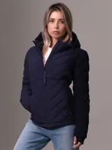 Campera acolchada azul marino con capucha, cierre de cremallera frontal y bolsillos laterales con cremallera. Diseño plegable con logo de Calvin Klein en la manga.