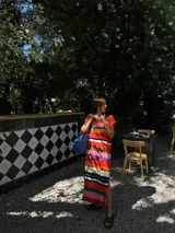 Vestido largo tejido con hilo de algodón a rayas horizontales en tonos marrón, beige, blanco y negro. Tiene cuello redondo y mangas cortas. Tejido a mano con terminaciones en crochet.