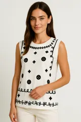 Musculosa blanca de algodón con bordados florales en negro, corte al cuerpo, cuello redondo y breteles anchos.