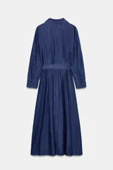 Vestido midi camisero de denim azul con cuello solapa y escote pico. Manga larga, bolsillos de parche con solapa en el delantero y laterales ocultos en costura. Incluye cinturón de la misma tela y cierre frontal con botones ocultos.