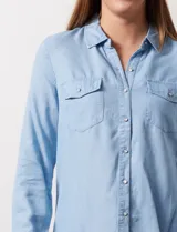 Camisa celeste de lyocell, marca Zac & Rachel. Cuello con solapa y abertura central con botones. Delantera con bolsillos.