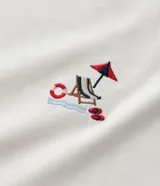 Remera color crudo de algodón con bordado de una escena playera en el pecho.