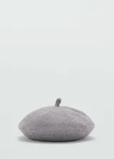 Boina gris de punto con detalle de rabito en la parte superior.