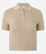 Blusa color beige de tejido de punto con textura cuadriculada, corte crop, cuello polo con cierre de botones y mangas cortas ajustadas.