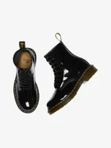 Bota acordonada de charol negro con costuras amarillas en la suela y tirador trasero con el logo de la marca.