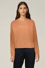 Buzo color naranja claro, con diseño oversize y mangas largas.