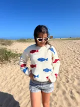 Sweater de lana color crema con diseño de peces bordados en azul y rojo. De corte holgado y mangas largas.