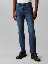 Pantalón de jean azul oscuro, corte slim, con bolsillos delanteros y traseros, cierre con cremallera y botón.