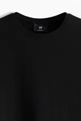 Remera negra de corte ajustado, confeccionada en punto de algodón liviano, con cuello redondo ribeteado y bajo recto.