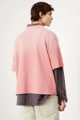 Remera rosa con efecto desteñido, corte amplio, cuello redondo y mangas cortas.