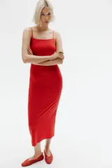 Vestido midi rojo de punto suave, corte entallado, con escote redondo profundo, espalda escotada y breteles spaghetti que se entrelazan en bucles y se atan en la espalda.