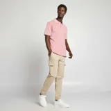 Remera polo de piqué color salmón con cuello y mangas con ribete blanco.