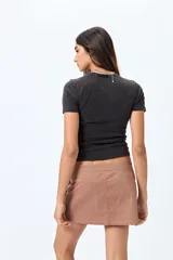 Minifalda color marrón claro, de corte recto con cierre metálico visible al frente y bolsillos decorativos con tachas.