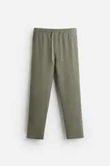 Pantalón de jogging color beige confeccionado en tejido de mezcla de algodón. Cuenta con cintura elástica ajustable con cordón, bolsillos frontales y traseros.