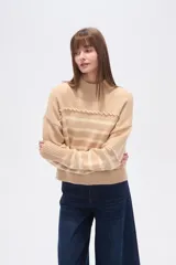Sweater beige con rayas horizontales negras, cuello alto y corte holgado.