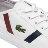 Championes Lacoste Sideline blancos de lona, con logo de la marca en el lateral, detalles en azul y bordó, y refuerzo en gamuza en el talón.