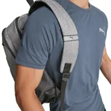 Mochila Puma unisex color gris con detalles en negro. Tiene un compartimento principal con cierre, un bolsillo frontal con cierre y un bolsillo lateral de malla. El logo de Puma está estampado en relieve en el frente.