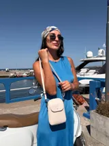 Bandolera pequeña y compacta color amarillo mostaza, realizada en símil cuero. Posee un bolsillo frontal con tapa y broche metálico, y un compartimento principal con cierre superior. Incluye correa ajustable del mismo material.