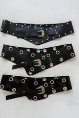 Cinto ancho de cuero negro con textura croco, con hebilla metálica plateada y apliques de tachas o ojalillos metálicos.