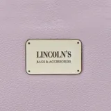 Billetera larga negra con cierre perimetral y placa metálica con logo. Posee múltiples compartimentos internos para tarjetas y documentos, además de un bolsillo con cierre interior. Incluye correa de mano desmontable.