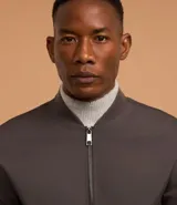 Campera bomber de poliéster color gris oscuro, con cuello alto, cierre frontal con cremallera, bolsillos laterales, mangas largas con puños ajustados y bajo con ajuste elástico.