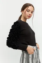 Remera negra de punto con mangas largas abullonadas con volantes.