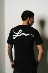 Remera negra de corte regular fit, con un pequeño parche ovalado estampado en el pecho y un gran logo de estilo manuscrito en la espalda.